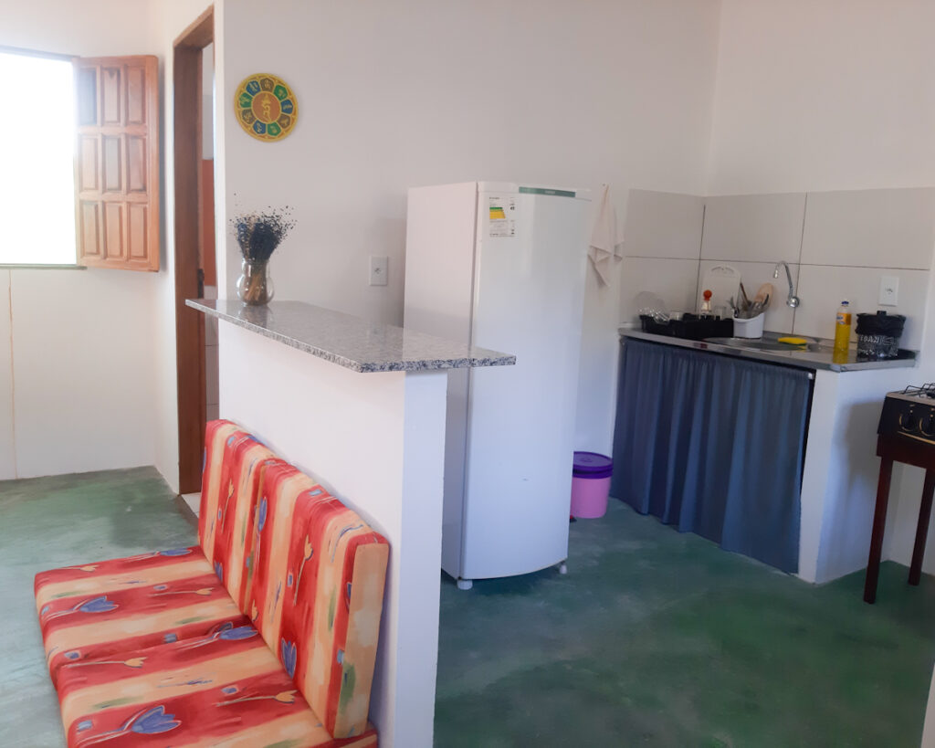 Sala e cozinha integrada de aconchegante chalé em Piatã