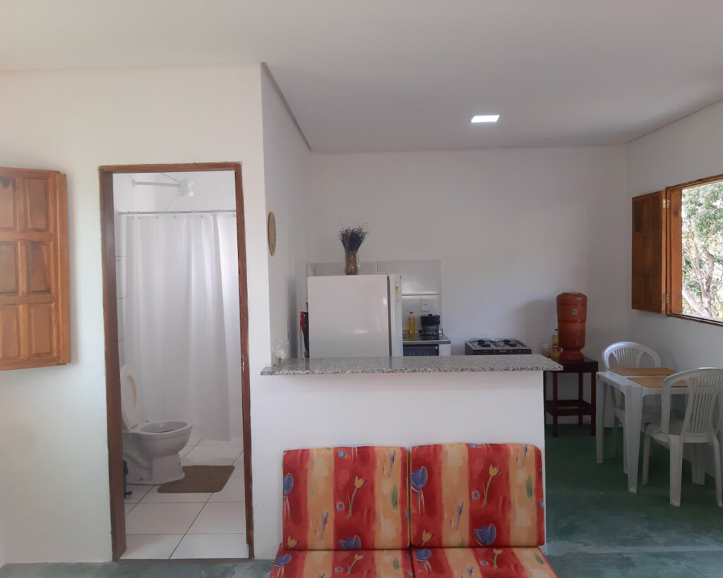 Sala e cozinha integrada de aconchegante chalé em Piatã