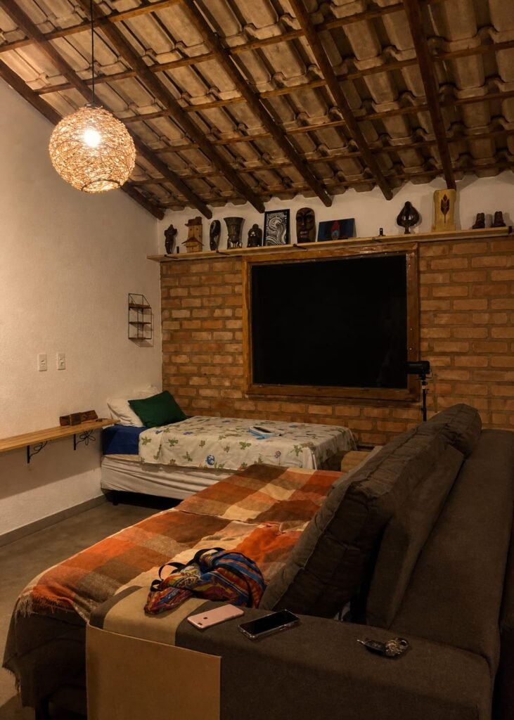 Quarto e sala com sofá e cama em casa em meio à natureza no Bosque do Lapão em Lençois na Chapada Diamantina