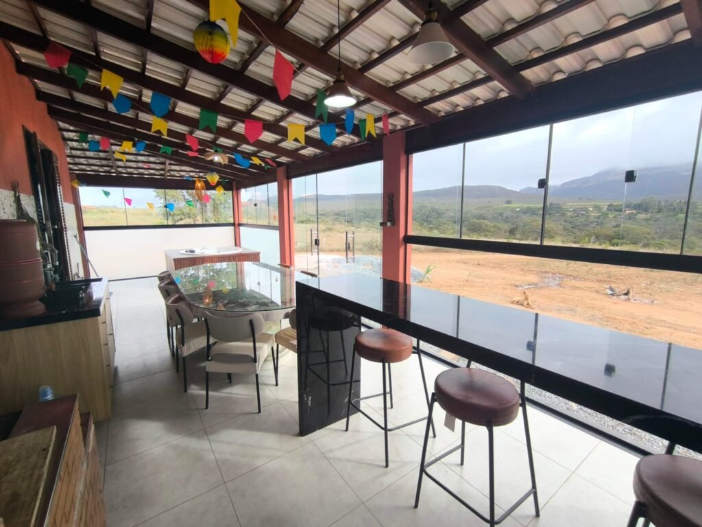 Varanda ampla e fechada com vidro com vista para as montanhas de casa com acabamento fino para locação temporária em Piatã, Chapada Diamantina, Bahia